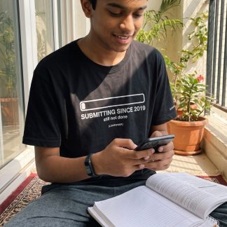 Kabir Nair wearing the LOWPOWER Submitting Since 2019 statement tee, home balcony scene