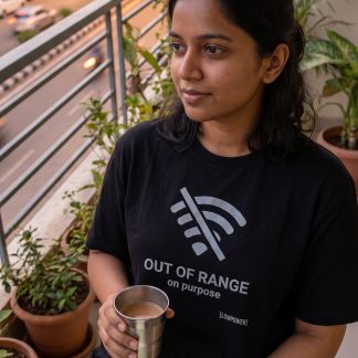 Priya Reddy wearing the LOWPOWER Out of Range statement tee, home balcony scene